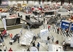 A photo taken from above of people setting up a trailer show in a giant expo hall
