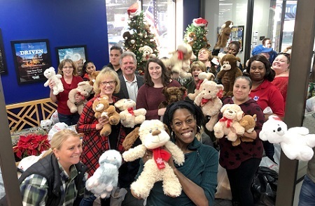 A photo of approximately a dozen people at PPL Motor Homes holding up stuffed animals in honor of the Cuddles for Kids Program