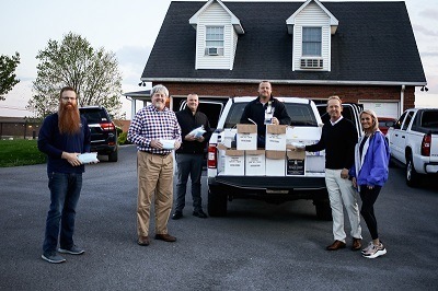 A picture of six people from Brown and Brown Dealer Services loading medical equipment and PPE into the back of a pickup.
