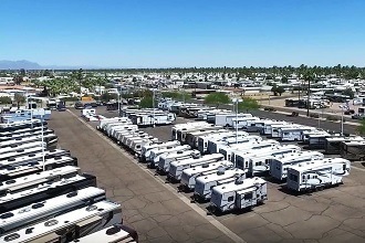 An aerial photograph of an RV dealership lot with dozens of RVs lined up neatly