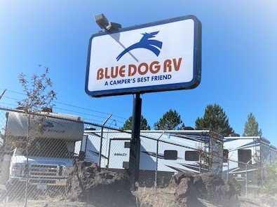 A photo of a sign that says "Blue Dog RV a Camper's Best Friend." The sign is above a lot that has RVs parked in it.