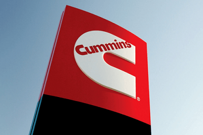 A picture of a sign with the Cummins logo in front of a clear blue sky