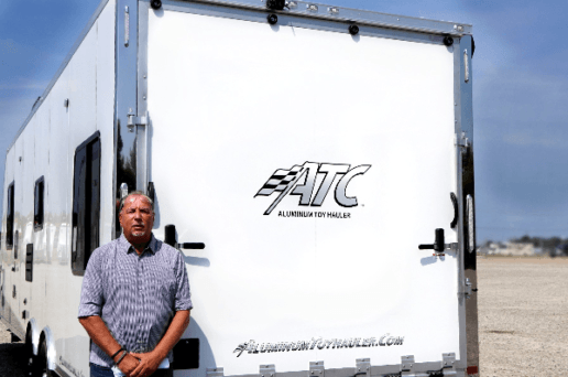 A picture of Jeff Gee standing beside a white cargo trailer that shows the Aluminum Trailer Company logo on it