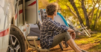 woman sitting next to an RV at campground