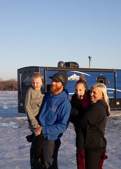 A picture of the Salzburn family next to their Ice Fish House