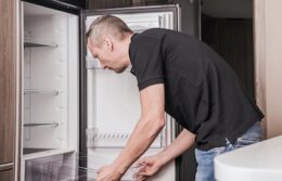 A picture of a man repairing a refrigerator