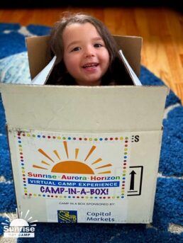 A picture of a Care Camps kid in a "Camp in a Box" package