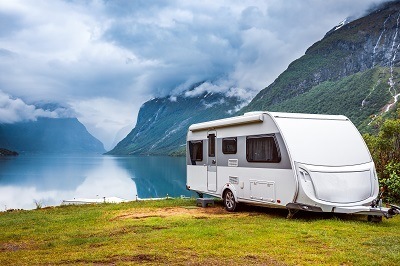 A picture of a general travel trailer parked by a lake