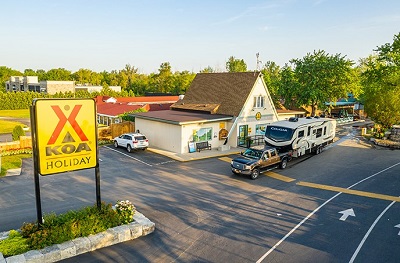 A picture of the entrance to a KOA campground, with a pickup hauling a Keystone RV Cougar fifth wheel