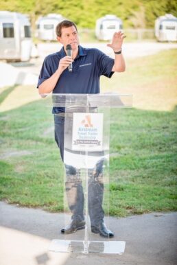 A picture of RV Retailer President and CEO Jon Ferrando speaking at a podium outside before a groundbreaking at a dealership site in Buda, Texas.