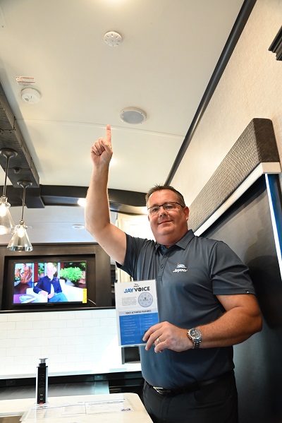A picture of director of product development Mike Aplin in a 2022 Jayco Pinnacle fifth wheel pointing to the JayVoice receiver in the ceiling