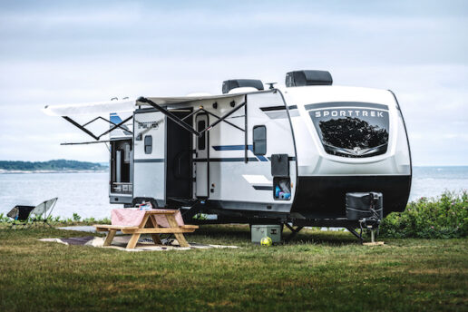 A picture of a Venture RV SportTrek travel trailer parked outside a lake