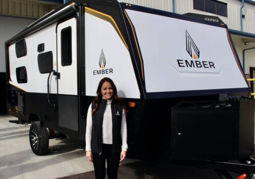 A picture of Ashley Bontrager Lehman, founder of Ember RV, standing next to the first completed Ember trailer in Bristol, Ind.
