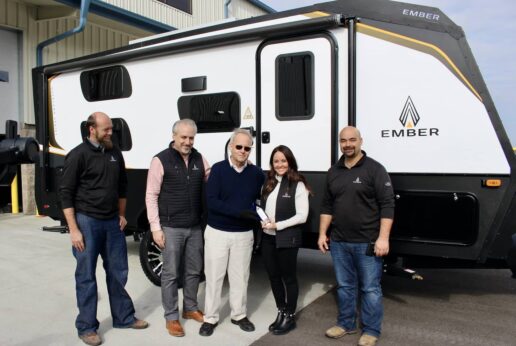 Ashley Bontrager Lehman, founder of Ember RV, stands next to the first completed Ember trailer in Bristol, Indiana with members of the Ember RV team and Haylett Automotive and RV team, which received the first unit.