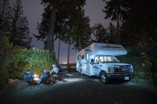 A picture of a Type C motorhome in Canada with campers sitting nearby at night.