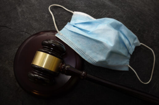 A picture of a face mask sitting next to a judges gavel.