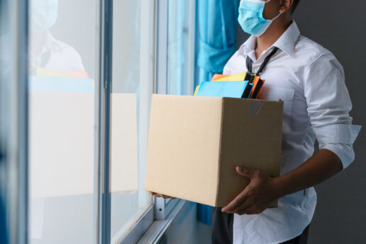 A picture of an employee holding a box of things while wearing a mask.