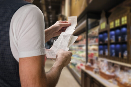 A young man checks the prices on a grocery receipt.