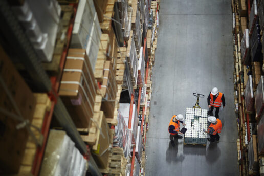 Top view of workers looking at products on a moving pallet in a warehouse setting