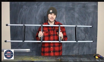 A picture of man in plaid shirt holding up RV bunk ladder.