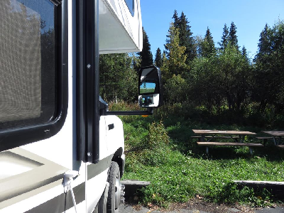 A picture of a motorhome parked at a campsite looking at an empty picnic table