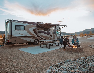 A picture of a couple outside an RVshare rental motorhome parked at a campground