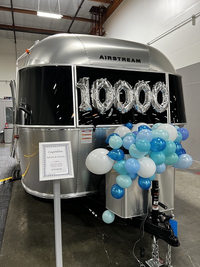 A picture of an airstream trailer with balloons and 10000 in window.