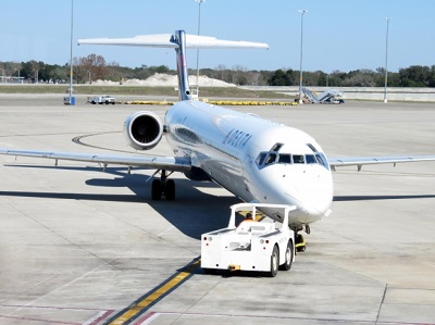 A picture of an airplane with a cargo truck at an airport