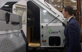 A picture of a man standing by an A-liner RV