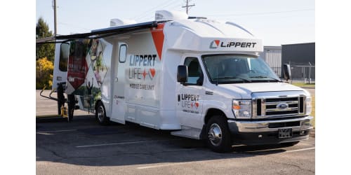 A picture of the Lippert Mobile Care Unit, an orange and white RV with awnings.