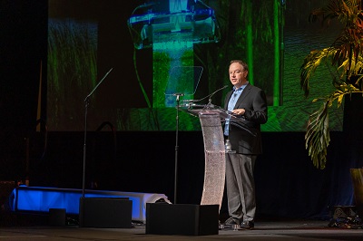 A picture of Winnebago President and CEO Michael Happe at a podium at the Newmar Dealer event April 2022