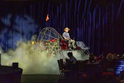 A picture of a man in a hat on a stage surrounded by clouds of smoke at the Newmar Dealer event