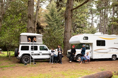 A picture of two families camping with a pop-up camper and a Class C camper.