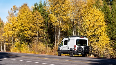 A picture of a Mercedes Sprinter Van on the road in the autumn