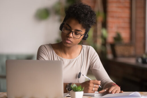 A picture of a female student at a computer taking notes