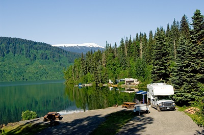 A picture of a truck camper at a campsite overlooking a lake and a forested hill