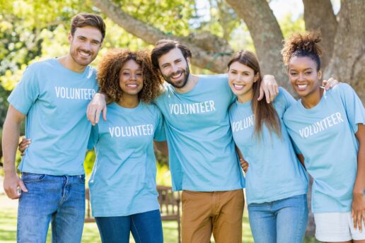 A picture of five diverse volunteers outside in matching shirts