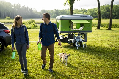 A picture of an open Sylvan Sport Loft Trailer with a Couple and their dog