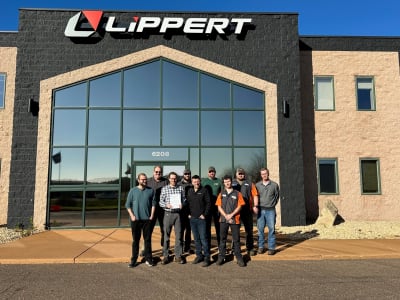 A picture of Curt staff outside a Lippert building with the company's ISO 14001 certification