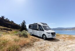 An exterior picture of the 2023 Leisure Travel Vans Unity MBL Type B motorhome parked in front of a lake