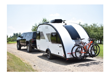 A picture of the Little Guy Max teardrop RV being towed down the street.