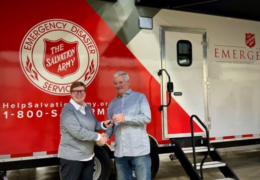 A picture of Mike Schoeffler handing the Embassy Salvation Army trailer keys to Bobbi Geery.