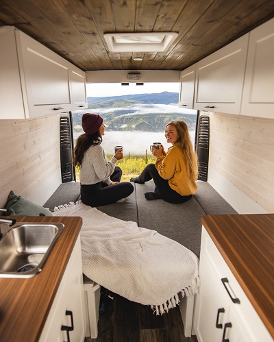 A picture of two women in a camper van drinking hot beverages from mugs