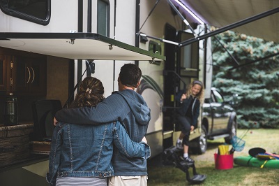 A picture of a family camping outdoors with a motorhome