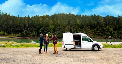 A stock photo of consumers shaking hands outside a Type B motorhome before renting the vehicle from a peer