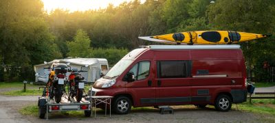 A picture of a Type B camper van with a kayak on top in front of two motorcycles