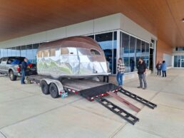 A picture of the restored Airstream Clipper being moved into the Airstream Heritage Center.