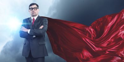 A picture of a man in a suit and glasses with a red cape