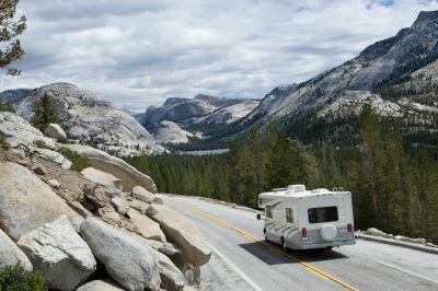 A picture of a Type C motorhome on the road in the mountains going downhill