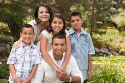 A picture of a Hispanic mom, dad and kids outside